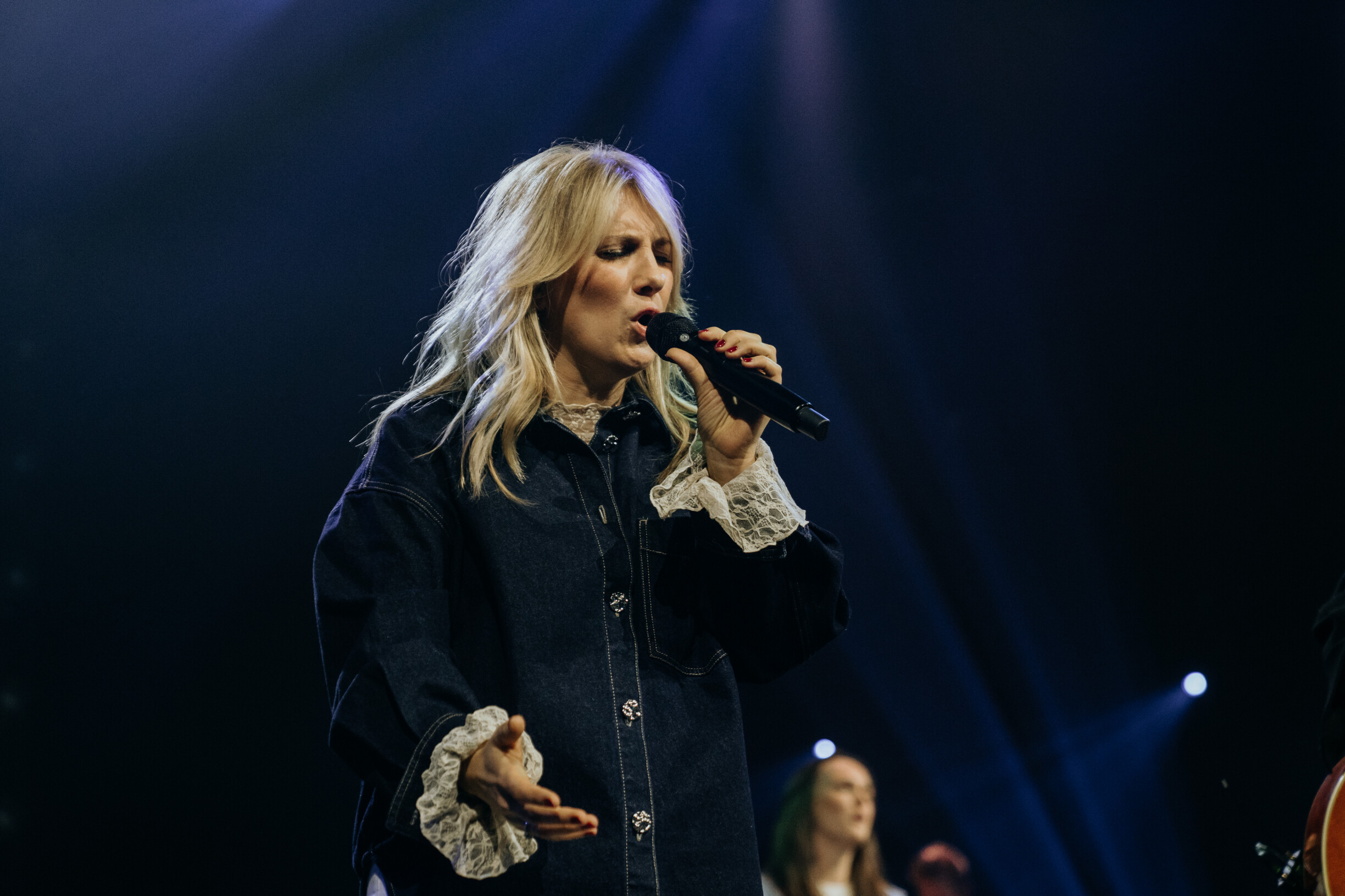 Zangeres van Mozaiek Worship zingt in de microfoon tijdens de albumopname