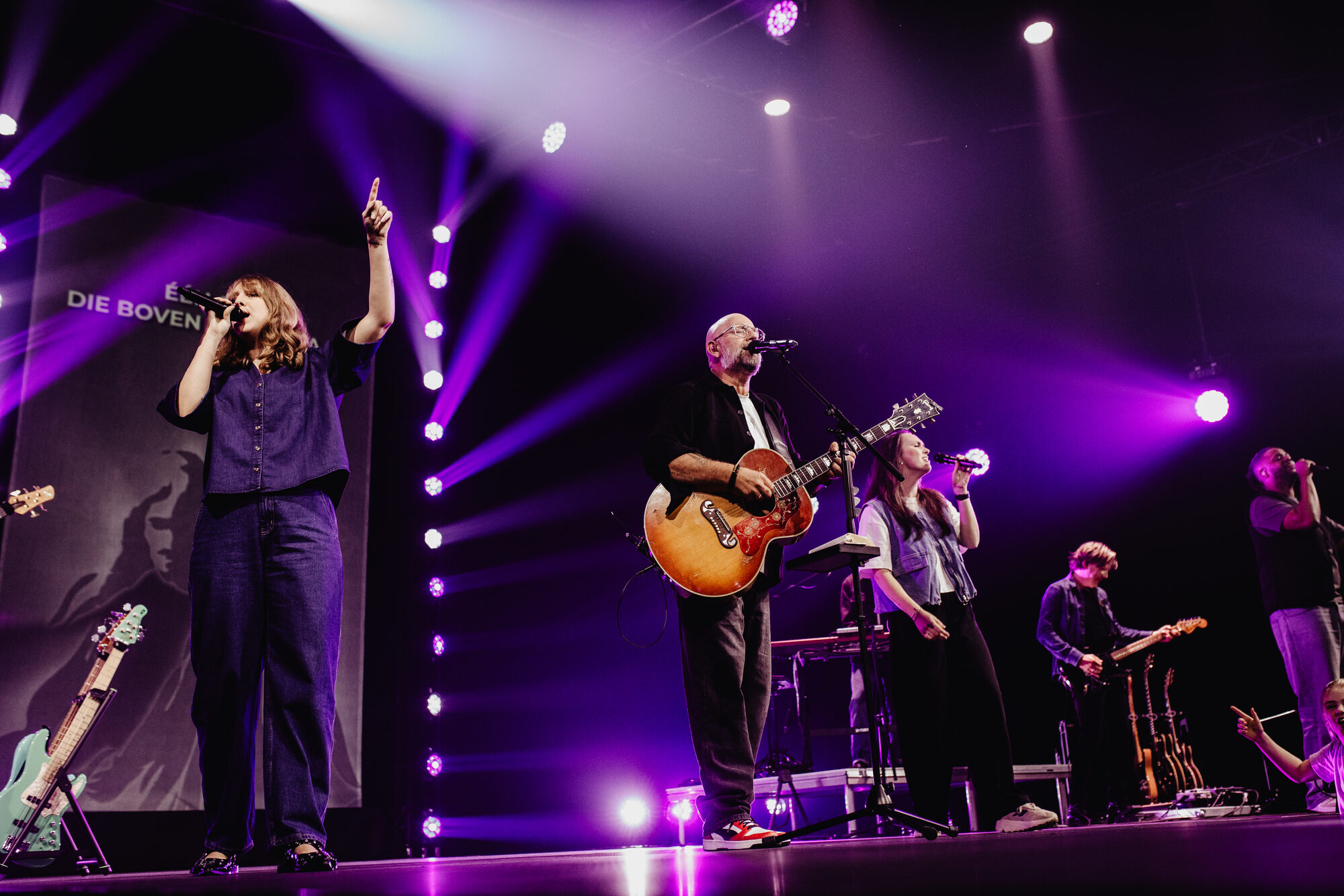 Mozaiek Worship op het podium in blauw podiumlicht