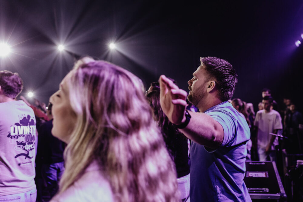 Twee bezoekers zingen mee met gevouwen handen tijdens de live-opname