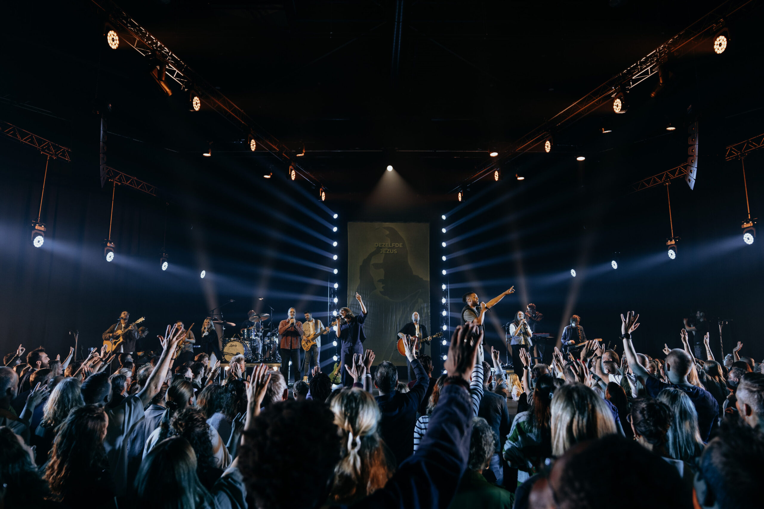 Publiek met opgeheven handen voor het verlichte podium tijdens de live-opname van Jezus Messias