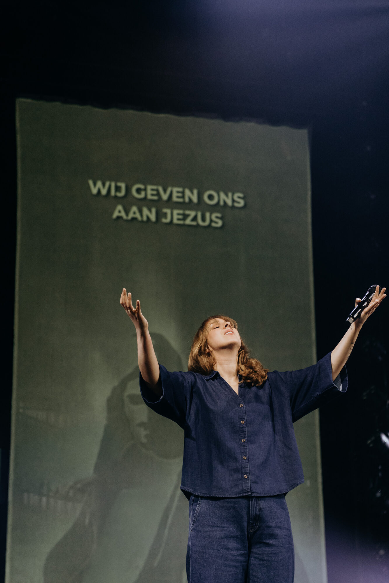 Reni Kraayenoord met opgeheven handen bij de liedtekst Wij geven ons aan Jezus