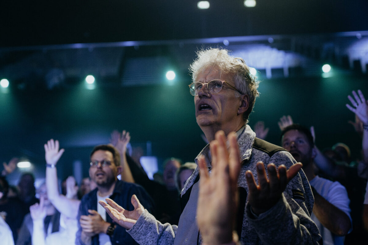 Handen omhoog in de zaal tijdens de aanbidding