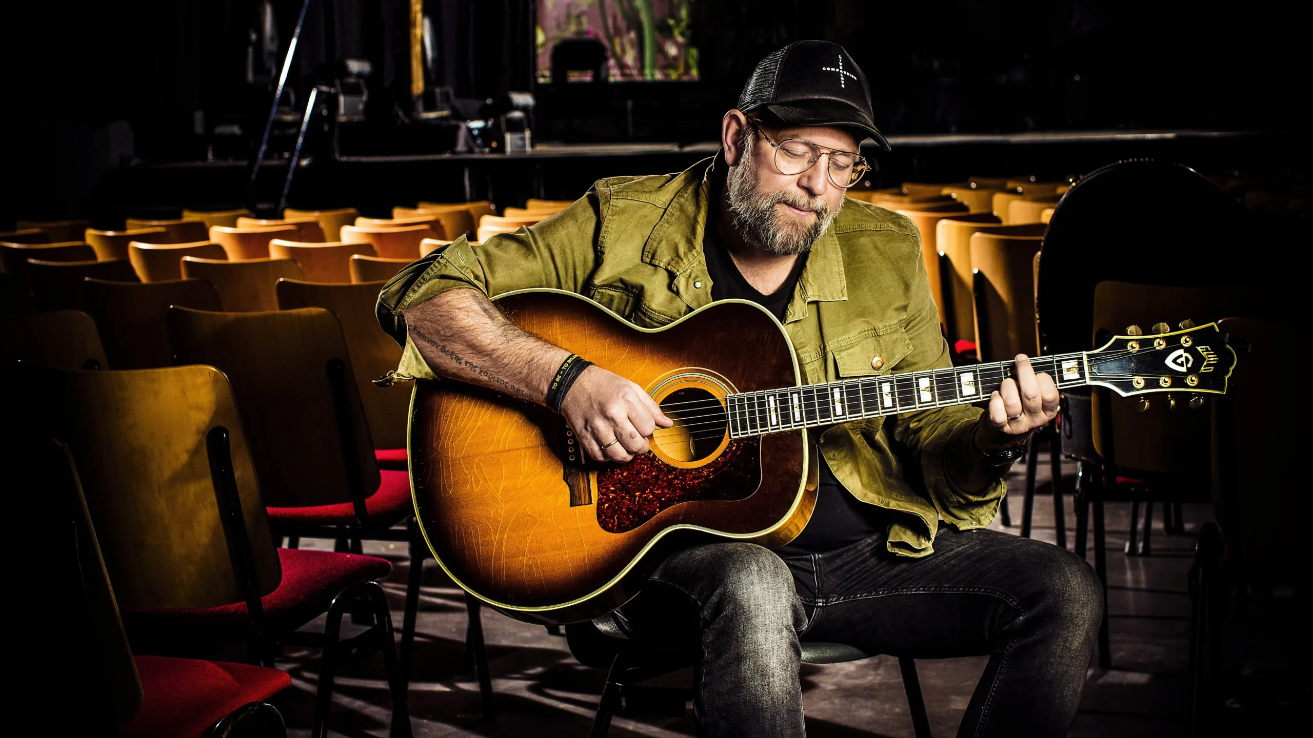 Kees Kraayenoord van Mozaiek Worship met akoestische gitaar in een lege kerkzaal